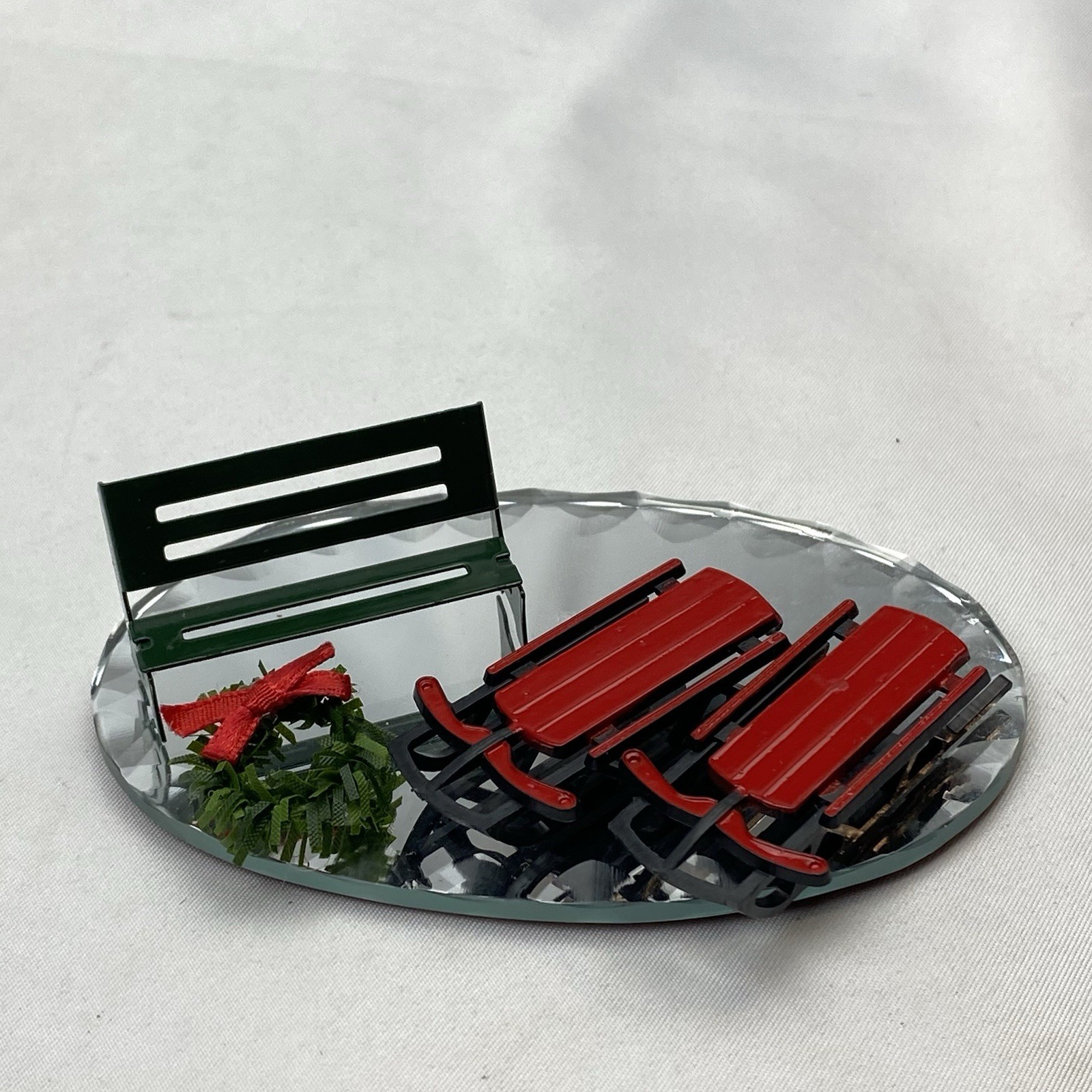 Christmas Village Sleds, Park Bench, Wreath With A Bow, And Mirror Brand Unknown